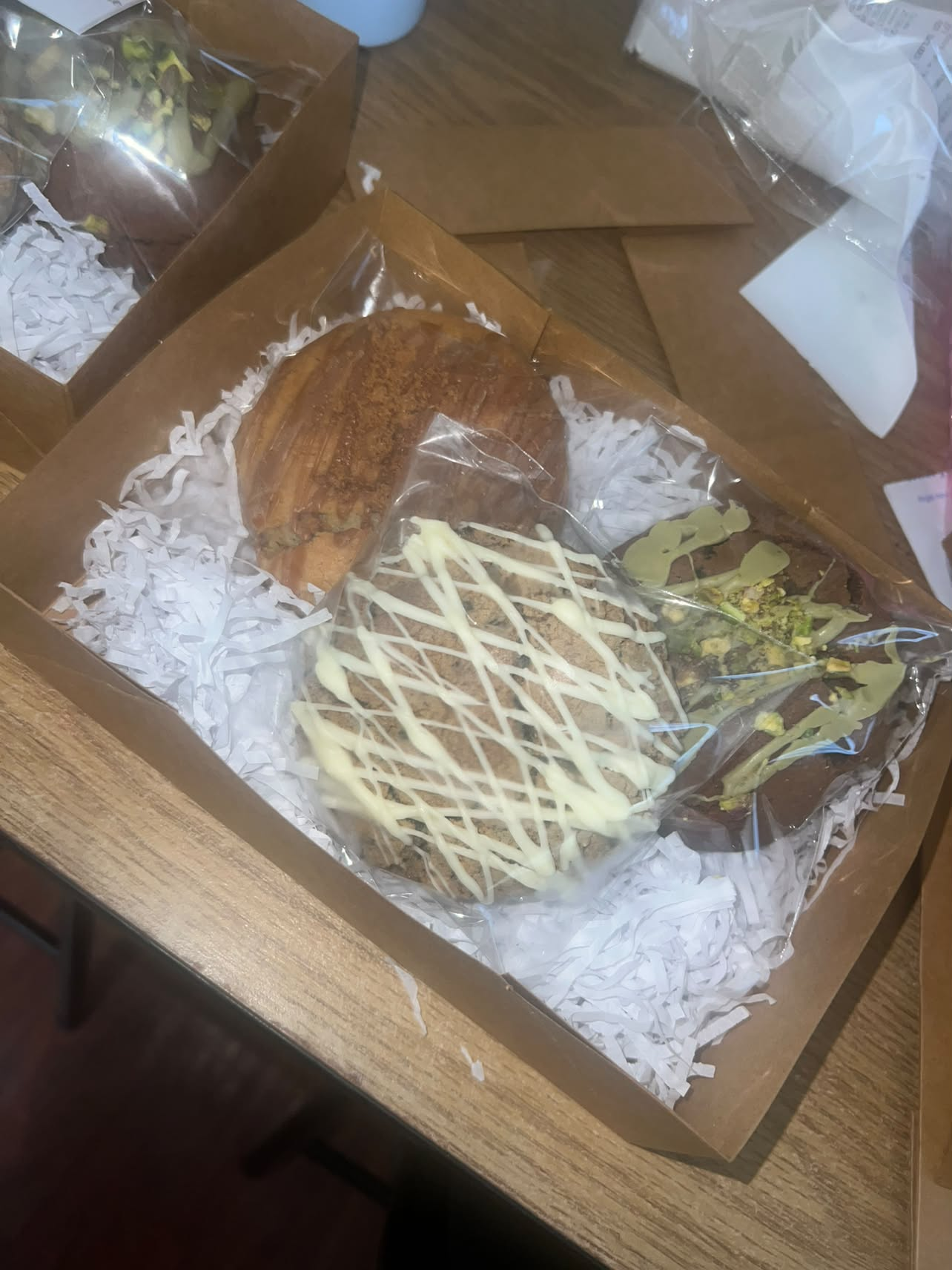 A box of Bella & Bloom cookies with drizzled and pistachio topped bakes